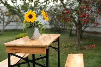 Photo of Vase with sunflowers on wooden table in garden