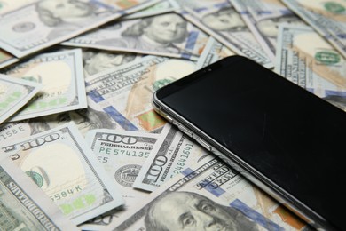 Photo of Modern smartphone on dollar bills, closeup view