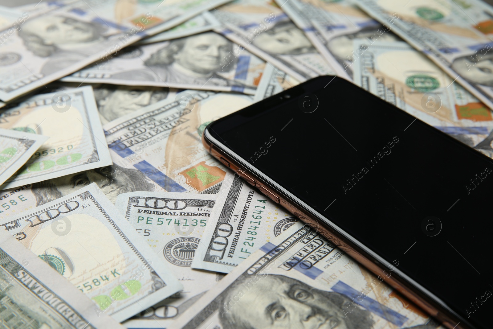 Photo of Modern smartphone on dollar bills, closeup view