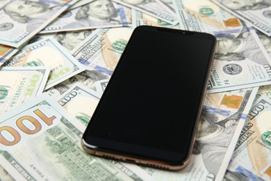 Photo of Modern smartphone on dollar bills, closeup view