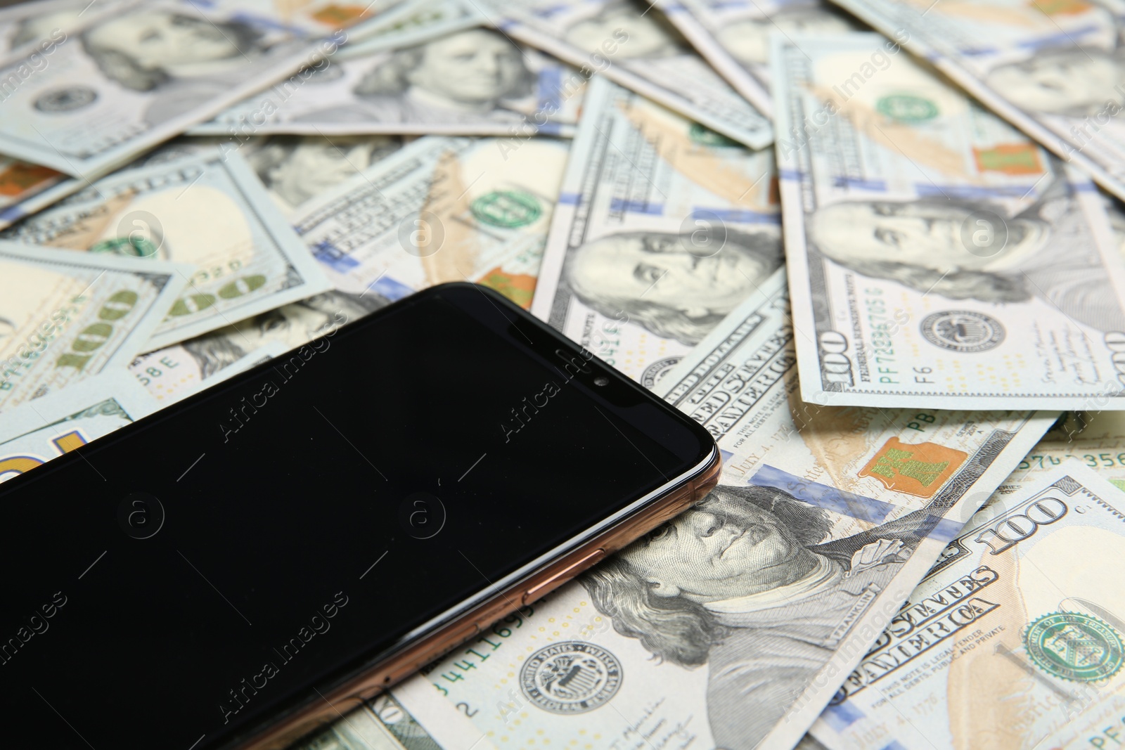 Photo of Modern smartphone on dollar bills, closeup view