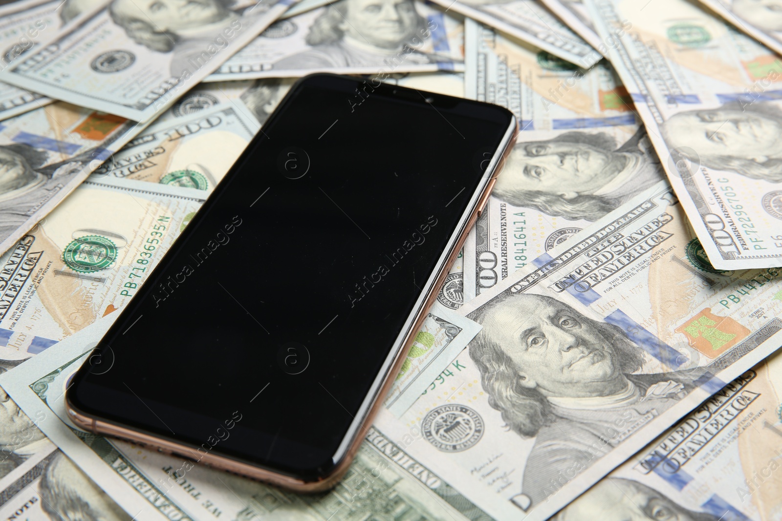 Photo of Modern smartphone on dollar bills, closeup view