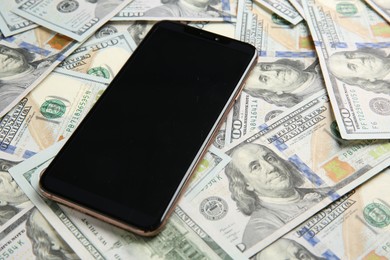 Modern smartphone on dollar bills, closeup view