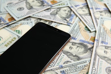 Photo of Modern smartphone on dollar bills, closeup view