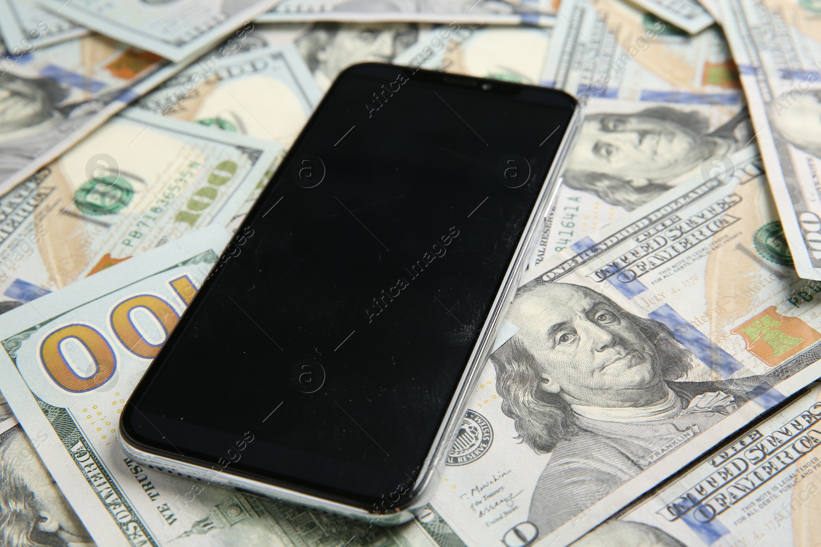 Photo of Modern smartphone on dollar bills, closeup view