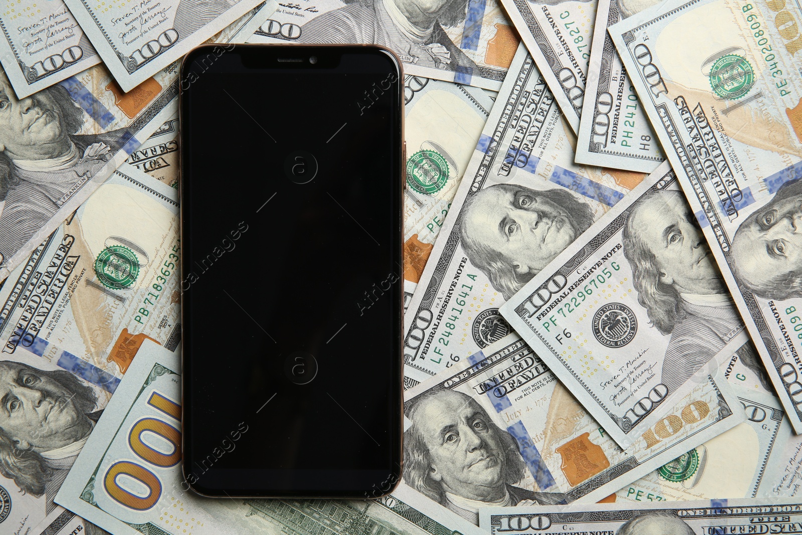 Photo of Modern smartphone on dollar bills, top view