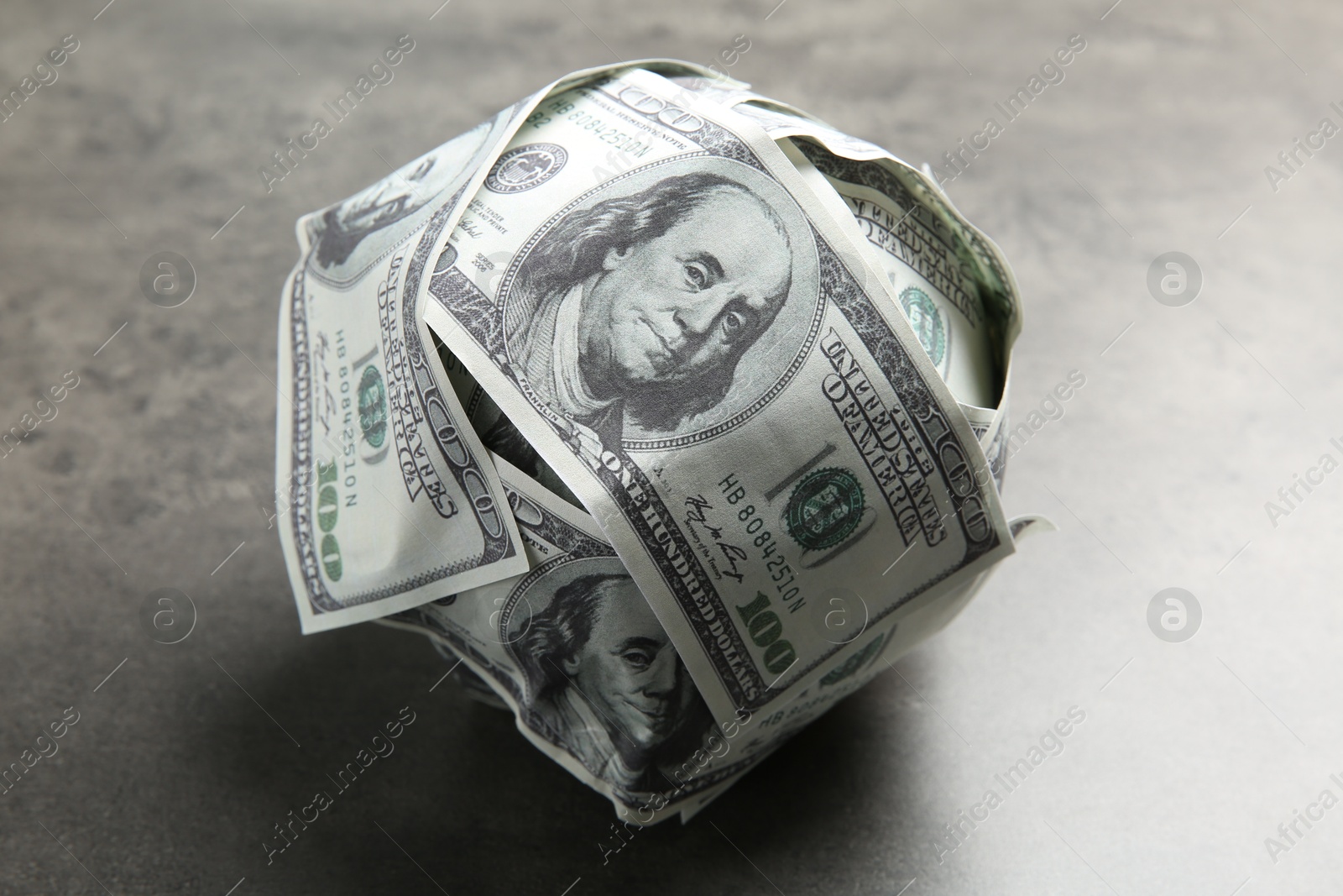 Photo of Ball made of dollars on grey table, closeup