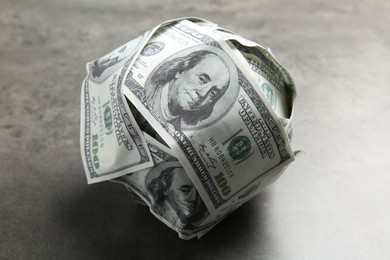 Photo of Ball made of dollars on grey table, closeup