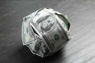 Photo of Ball made of dollars on grey table, closeup