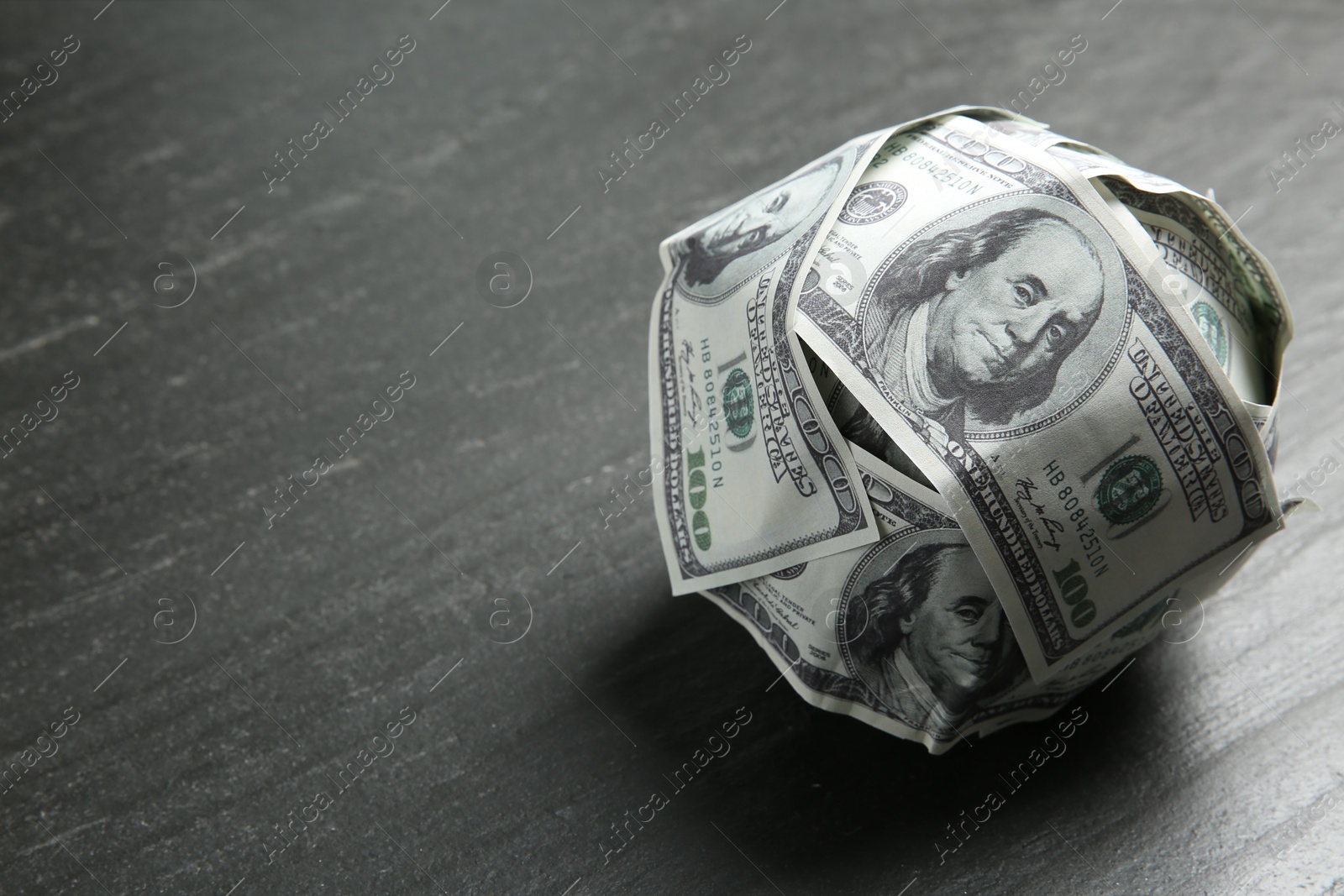 Photo of Ball made of dollars on grey table. Space for text