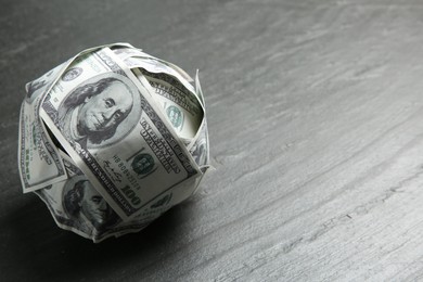 Photo of Ball made of dollars on grey table. Space for text