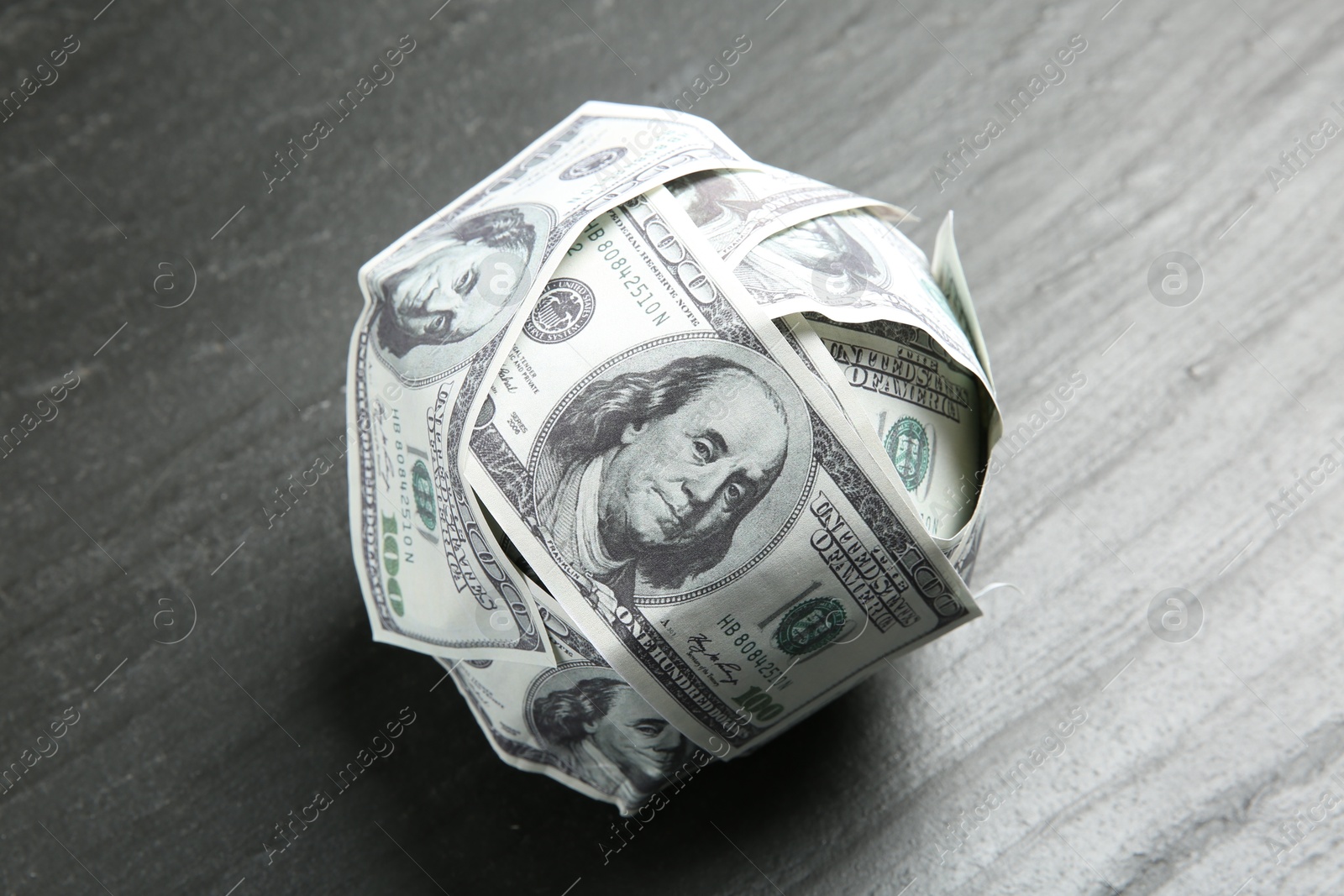 Photo of Ball made of dollars on grey table