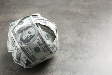 Photo of Ball made of dollars on grey table. Space for text