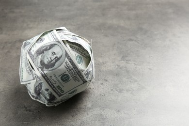 Photo of Ball made of dollars on grey table. Space for text