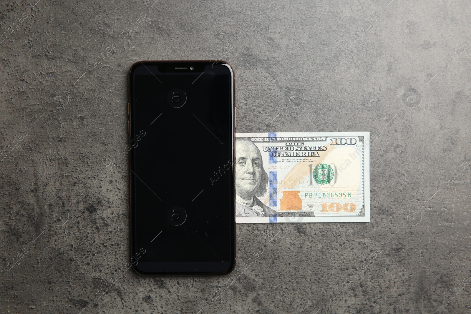 Photo of Modern smartphone and dollar bills on grey table, top view