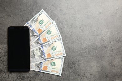 Photo of Modern smartphone and dollar bills on grey table, top view. Space for text