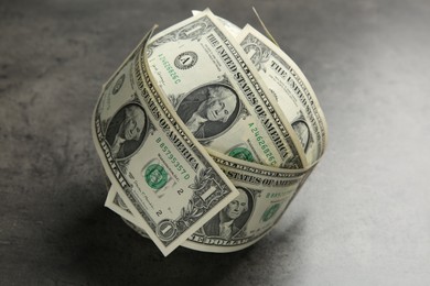 Photo of Ball made of dollars on grey table, closeup