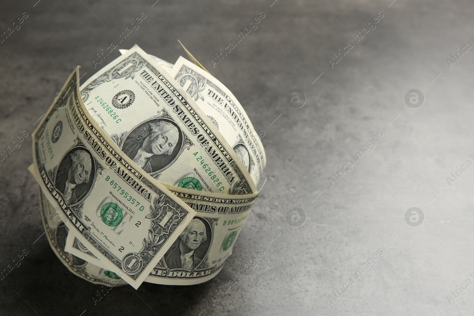 Photo of Ball made of dollars on grey table. Space for text