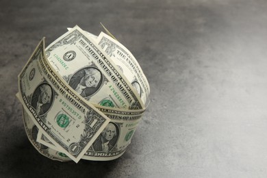 Photo of Ball made of dollars on grey table. Space for text