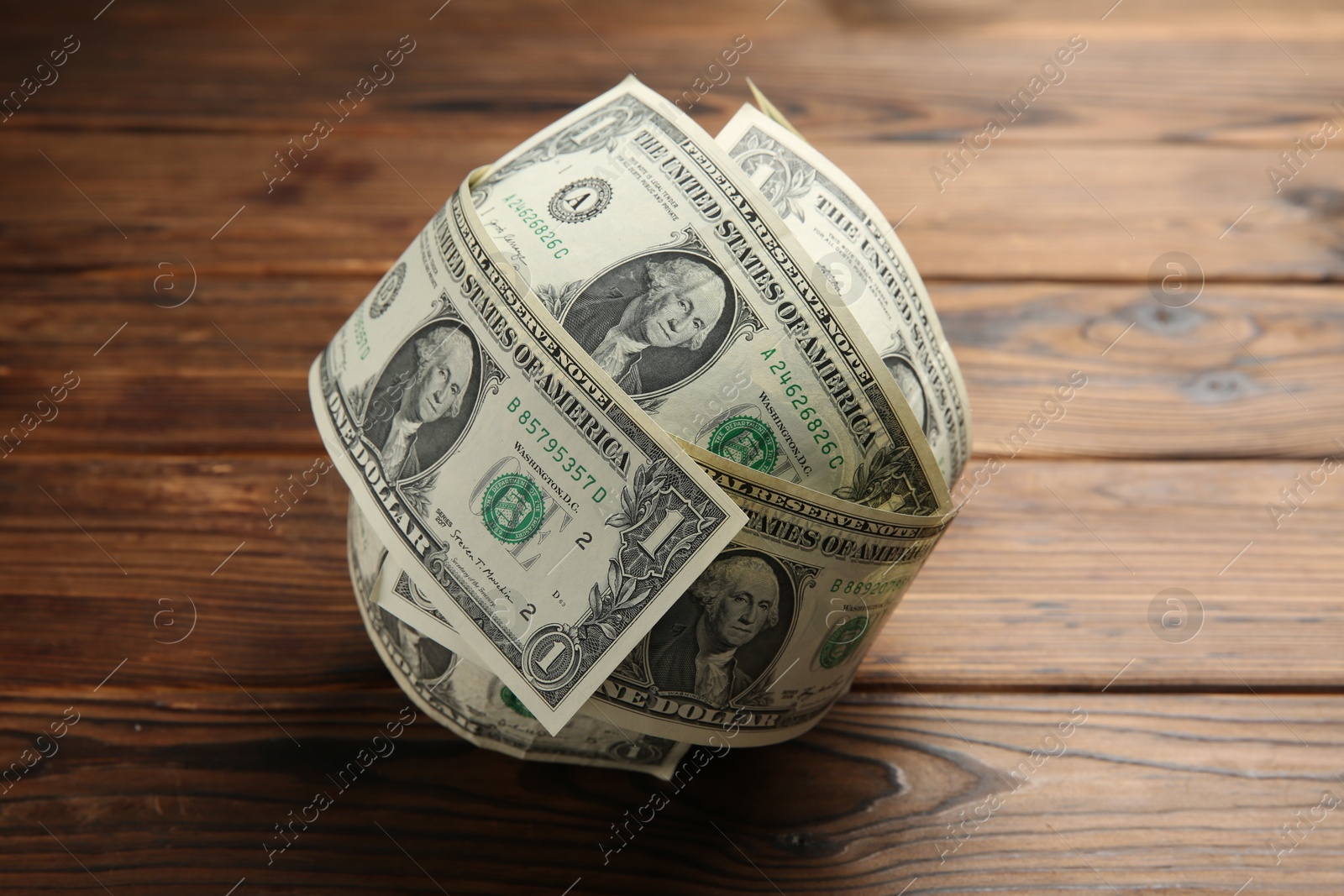 Photo of Ball made of dollars on wooden table