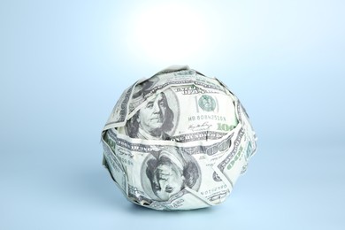 Photo of Ball made of dollars on light blue background