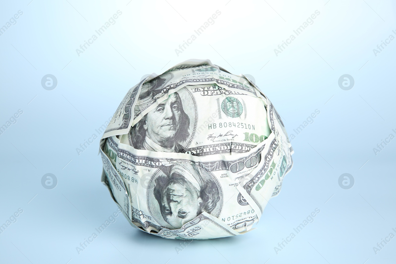 Photo of Ball made of dollars on light blue background