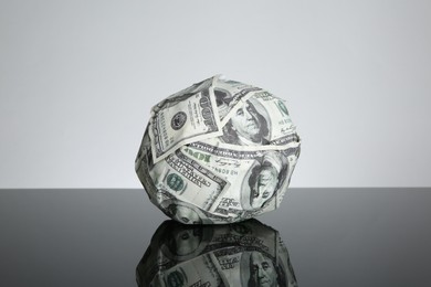 Photo of Ball made of dollars on black mirror surface