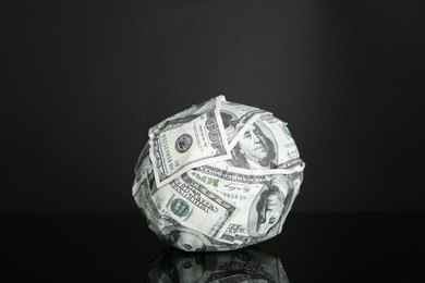 Photo of Ball made of dollars on black mirror surface