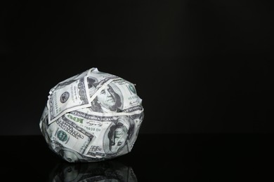 Photo of Ball made of dollars on black mirror surface