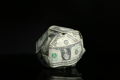 Photo of Ball made of dollars on black mirror surface