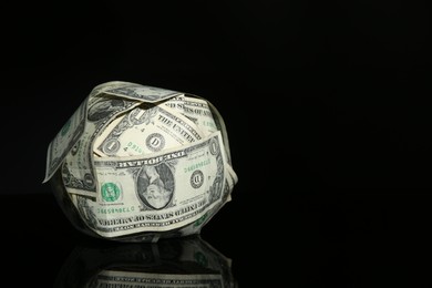 Photo of Ball made of dollars on black mirror surface. Space for text