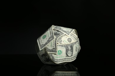 Photo of Ball made of dollars on black mirror surface