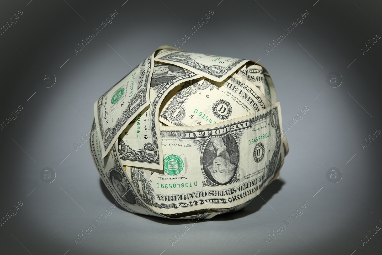 Photo of Ball made of dollars on grey background