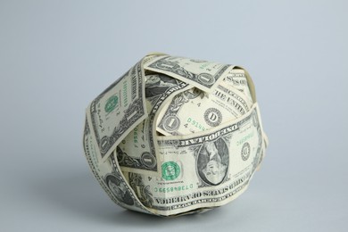 Photo of Ball made of dollars on light grey background