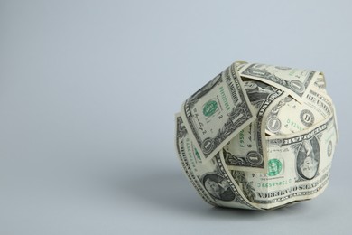 Photo of Ball made of dollars on light grey background. Space for text