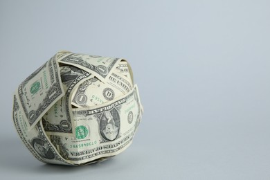 Photo of Ball made of dollars on light grey background. Space for text