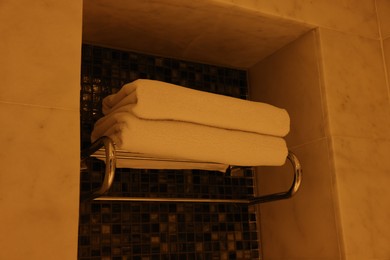 Heated rail with towels on wall in bathroom