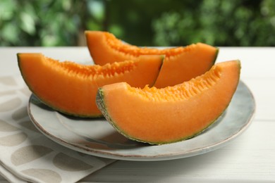 Photo of Pieces of fresh Cantaloupe melon on white wooden table, closeup