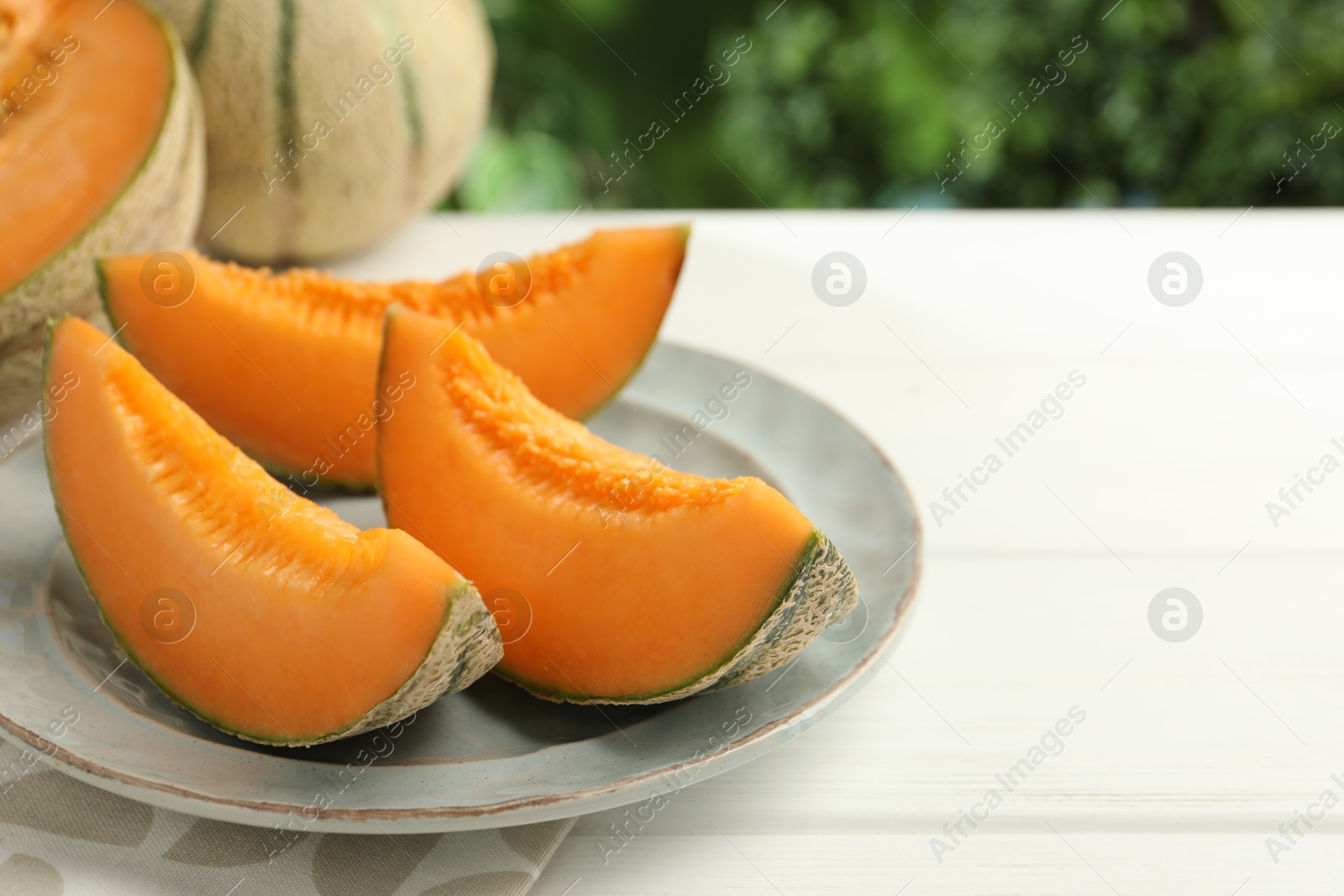 Photo of Pieces of fresh Cantaloupe melon on white wooden table, closeup. Space for text