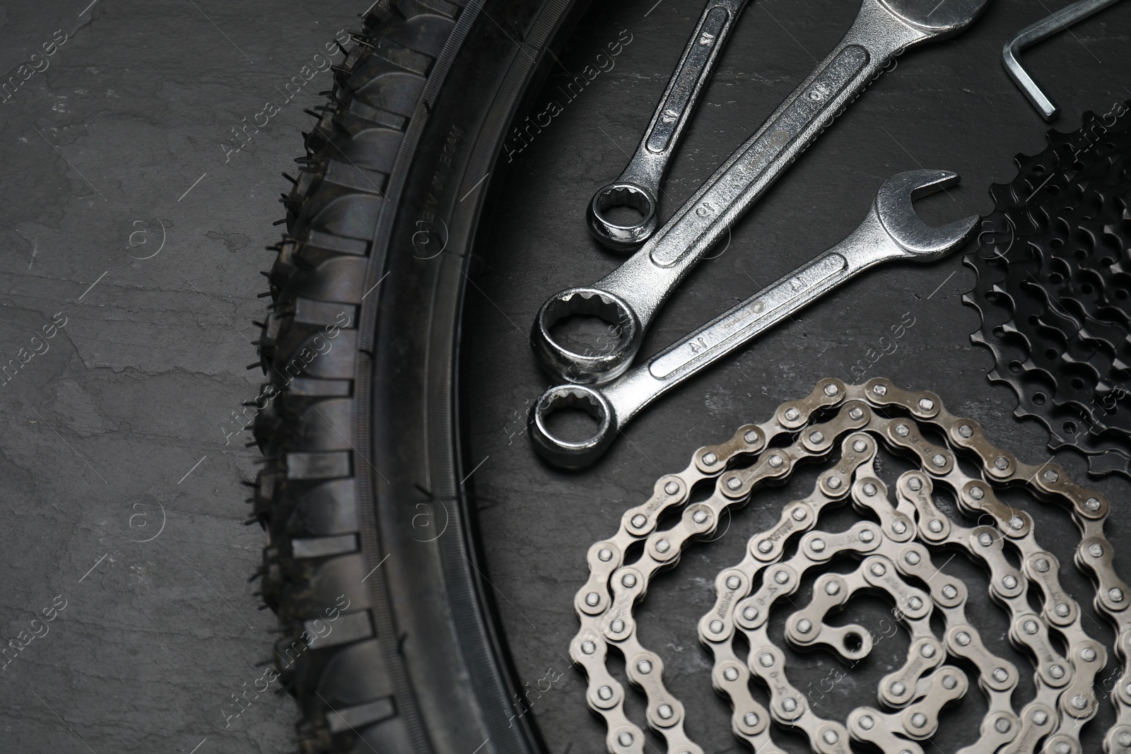 Photo of Parts of bicycle and tools on black table, above view. Space for text