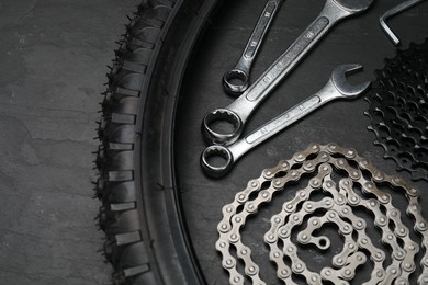 Parts of bicycle and tools on black table, above view. Space for text