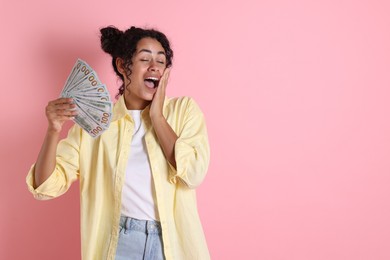 Shocked woman with dollar banknotes on pink background, space for text