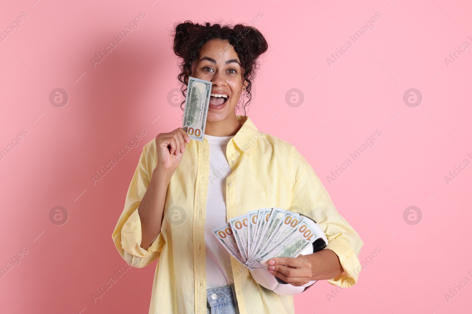 Photo of Happy woman with money and soccer ball on pink background