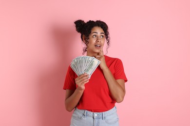 Woman with dollar banknotes on pink background