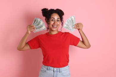 Happy woman with dollar banknotes on pink background