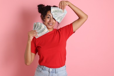 Happy woman with dollar banknotes on pink background