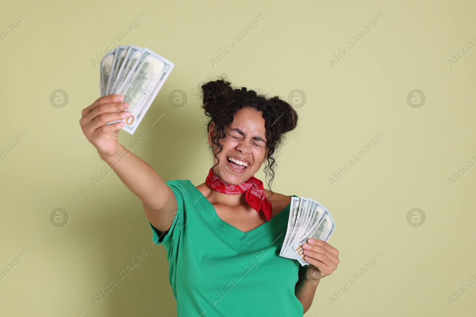 Photo of Happy woman with dollar banknotes on pale green background