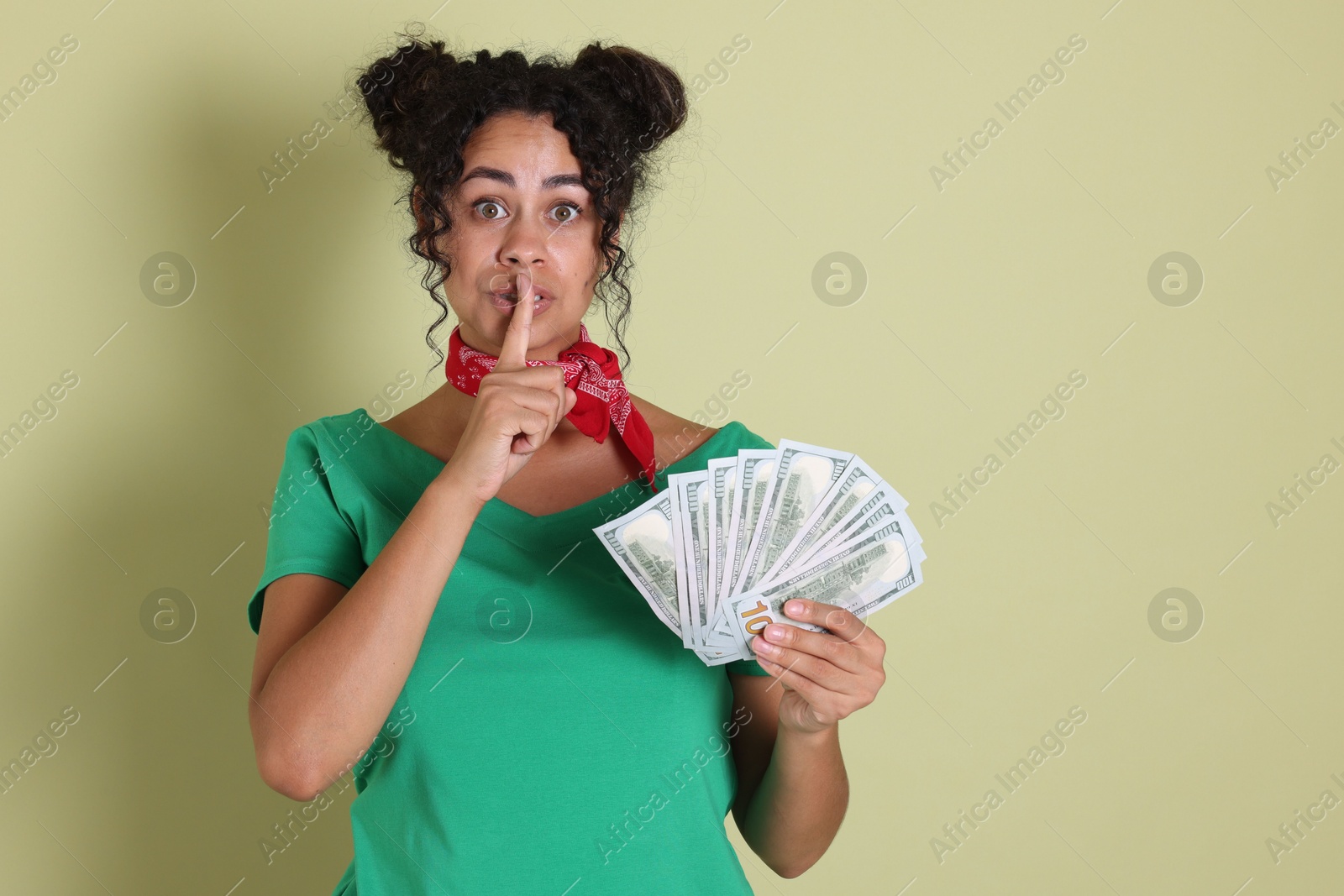 Photo of Woman with dollar banknotes making silent gesture on pale green background