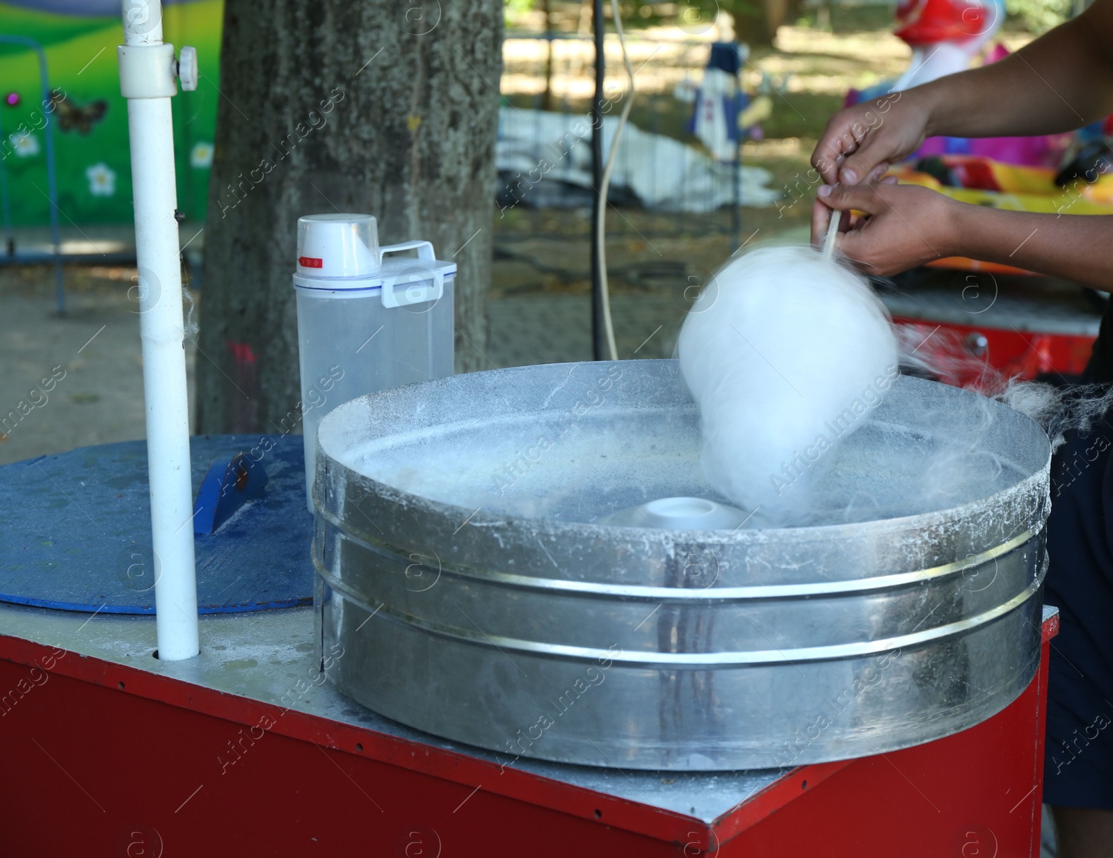 Photo of Man making cotton candy with machine outdoors, closeup