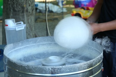 Photo of Man making cotton candy with machine outdoors, closeup